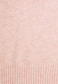 Ljust rosa stickad tyg med en mjuk struktur och ribbad nederkant. Jämn färg med subtila nyansvariationer.