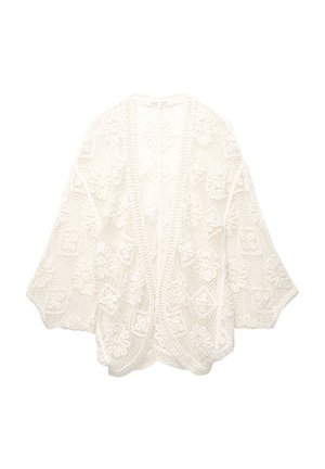 Gilet au crochet en coton blanc avec des motifs floraux, devant ouvert, manches larges et design de tissage texturé. Présente une coupe décontractée.