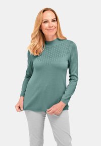 Strickpullover in Petrol mit einer strukturierten, gemusterten Passe. Lange Ärmel und runder Halsausschnitt. Weiches Material, lockere Passform, leichtes Rippenmuster am Saum.