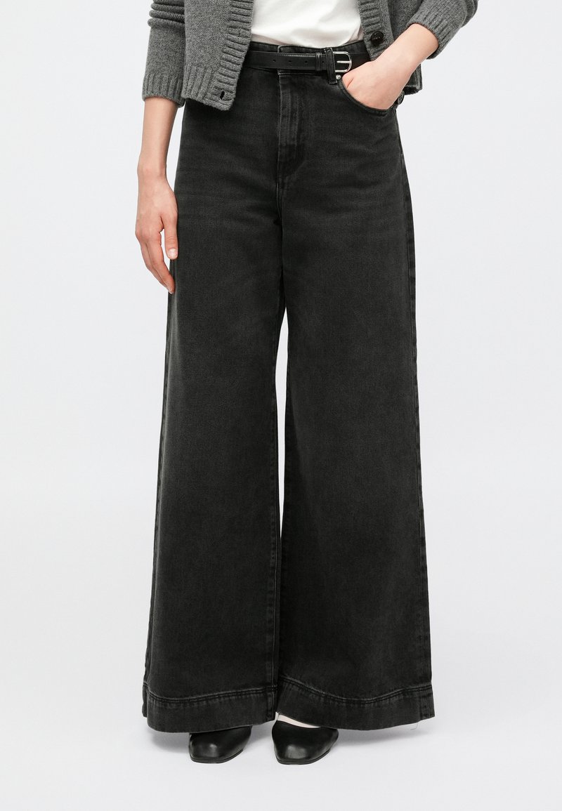 Laiade säärega mustad teksapüksid kõrge vöökohaga, millel on tihe kangas, minimaalne õmblus ning puhas ääreviimistlus. Sobitatud halli kardiganiga.