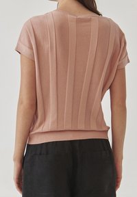 Světle růžový pletený top s vertikálním žebrovaným vzorem, krátkými rukávy a kulatým výstřihem. Spodní část má hladký, přiléhavý lem.