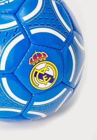 Modrá futbalová lopta s bielymi akcentmi, s textúrovanými vzormi a logom Real Madrid. Vyrobená z syntetického materiálu, guľatý tvar.
