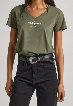 Oliivinvihreä V-mallinen t-paita, jossa valkoinen "Pepe Jeans London" -logo, yhdistettynä mustiin kapealahkeisiin farkkuihin ja mustaan vyöhön, jossa hopeanväriset yksityiskohdat.