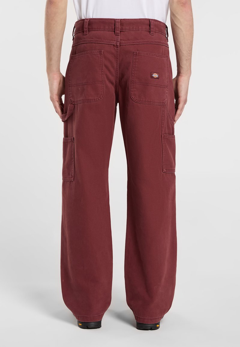 Burgunderfarvede cargo bukser lavet af slidstærkt stof. Funktioner inkluderer brede ben, flere lommer og et logo på baglommen.