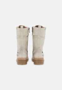 Beige leather ankle boots with a textured surface, zip closure, and a layered heel. Back features decorative straps and contrasting accents.