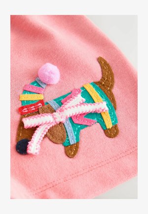 Tessuto rosa con un design di un cane colorato ricamato. Il cane ha macchie di marrone, turchese, giallo, rosso e un pon-pon rosa sul cappello.