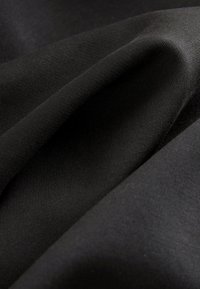 Black fabric, smooth texture with a slight sheen, showcasing draped folds; features subtle ribbing pattern, providing depth and interest.