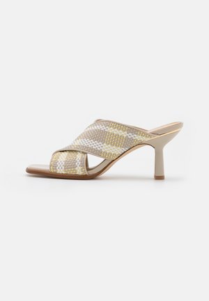 Mule ouvert tressé en beige, jaune et blanc, présentant un design à brides croisées, un talon fin et une texture lisse.
