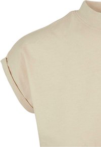 Haut beige à manches courtes avec revers retroussés et encolure ronde, en tissu côtelé doux.