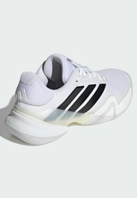 Bílá sportovní obuv s texturovaným svrškem, černými doplňky a třemi černými pruhy. Podešev je průsvitná s prohnutým designem.