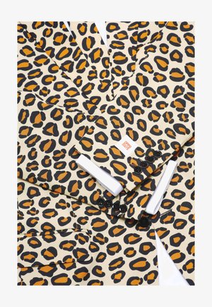 Sako s leopardím vzorom s krémovým podkladom, výraznými čiernymi a oranžovými vzormi, čiernymi gombíkmi a bielym rukávom košele, ktorý vykúka.