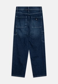 Mørkeblå denimbukser med rett snitt, med to påsydde lommer bak og minimale sømdetaljer. Ingen lommer synlig foran.