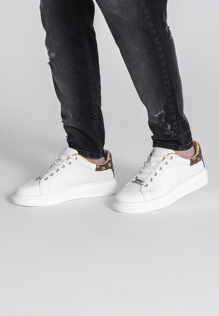 Weiße Sneakers aus glattem Leder mit einem kontrastierenden braunen Akzent an der Ferse, runder Zehenpartie und dicker weißer Sohle.