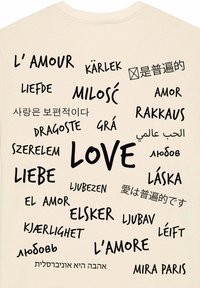 Beige t-shirt met verschillende woorden voor "liefde" in verschillende talen, gedrukt in vetgedrukte zwarte tekst, met variërende lettertypen en groottes.
