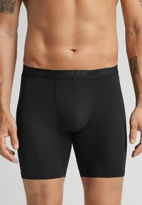 Boxer briefs negros hechos de una tela suave, con una cinturilla elástica de marca, longitud hasta el muslo y un diseño de bolsa contorneada.