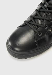Stivale nero con lacci in pelle liscia, caratterizzato da una punta arrotondata, lati texture, occhielli in metallo e una suola spessa in gomma.