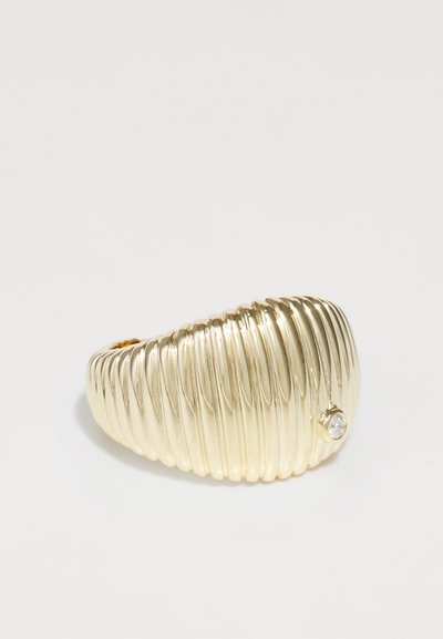 Bague dorée ornée d'un design à nervures avec une texture lisse. Accentuée par une petite pierre claire incrustée près de la bande.