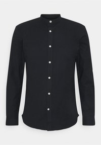 Camisa negra de manga larga con cuello alzado, tapeta frontal con botones blancos y un diseño ajustado. Textura de tela lisa y sólida.