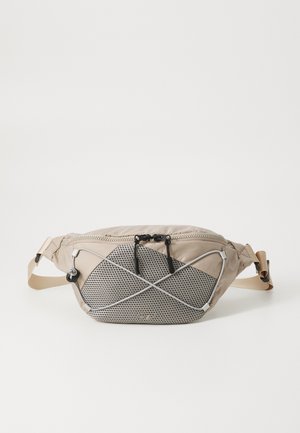 Beige fanny pack with mesh panel and black accents. Features a zipper closure, adjustable strap, and elastic cord detailing on the front.