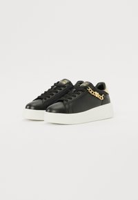 Black leather sneakers with white rubber soles, featuring black laces, gold chain detail on the side, and branded tags on the tongue.