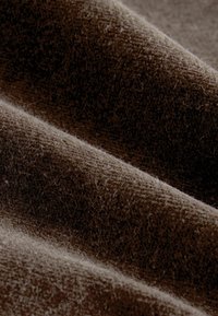 Brown fabric with a soft, textured surface featuring ripples and fur-like fibers. The color ranges from dark to light brown in different areas.