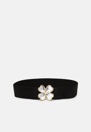 Ceinture large en tissu noir avec une boucle bordée d'or en forme de trèfle à quatre feuilles, ornée de pierres claires facettées.
