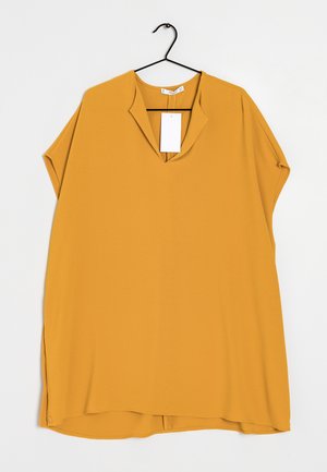 Sininen keltainen lyhythihainen pusero, jossa on V-pääntie ja sivuaukot. Valmistettu sileästä kankaasta, jossa on merkki kiinnitettynä kaula-aukkoon.