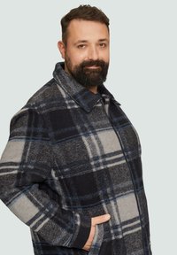 Wollmischung Karo-Jacke mit einem blau-grauen Muster, ausgestattet mit einem Reißverschluss-Vorderteil, breitem Kragen und seitlichen Taschen. Weiche Textur und lockerer Schnitt.
