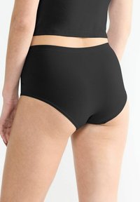 Schwarze, hochgeschnittene Unterwäsche mit glatter Textur und elastischem Bund, von hinten betrachtet, zeigt ein einfaches, nahtloses Design.