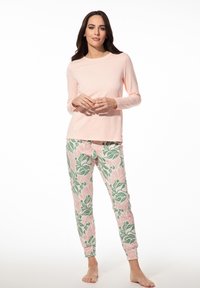 Lichtroze top met lange mouwen, gecombineerd met bloemenpatroon broek in roze en groene tinten. Zachte stof met een ontspannen pasvorm en enkelboorden.