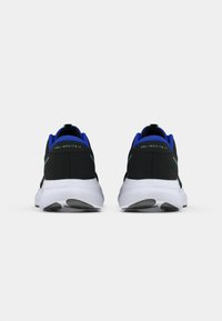 Μαύρα αθλητικά παπούτσια με ύφασμα πλέγματος, μπλε λεπτομέρειες, πράσινη επωνυμία και λευκές σόλες. Η φτέρνα διαθέτει στρογγυλό σχήμα και υφή.