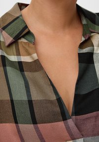 Blusa a quadri con colletto che presenta tonalità di verde, nero, rosa e beige. Tessuto leggero con scollatura a V e una sottile texture.
