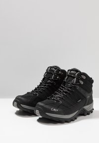 Schwarze Wanderschuhe mit einem hohen Design, hergestellt aus Stoff und Gummi, ausgestattet mit metallischen Beschlägen, strukturierten Akzenten und einer robusten Sohle.