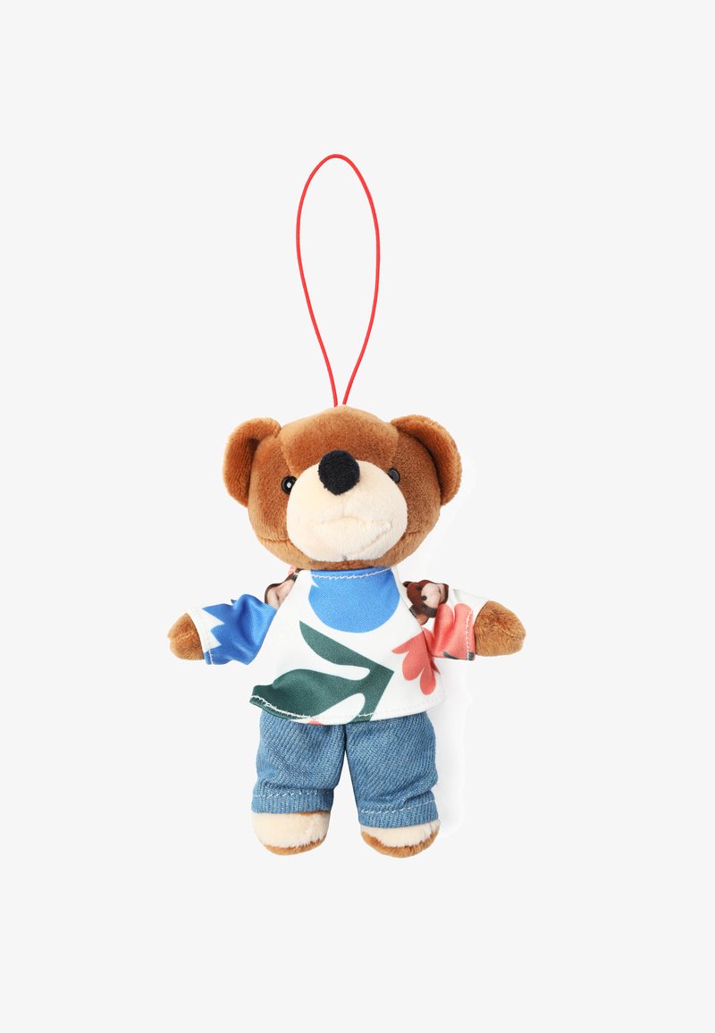 Plyšový medvídek jako přívěšek na klíče s hnědou kožešinovou tváří, oblečený v barevném květinovém tričku a modrých džínových kalhotách, má červenou zavěšovací smyčku.