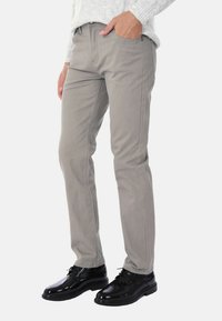 Pantaloni in denim grigio con una vestibilità slim, dotati di tasche anteriori e dettagli di cucitura sottili, abbinati a scarpe eleganti nere lucide.