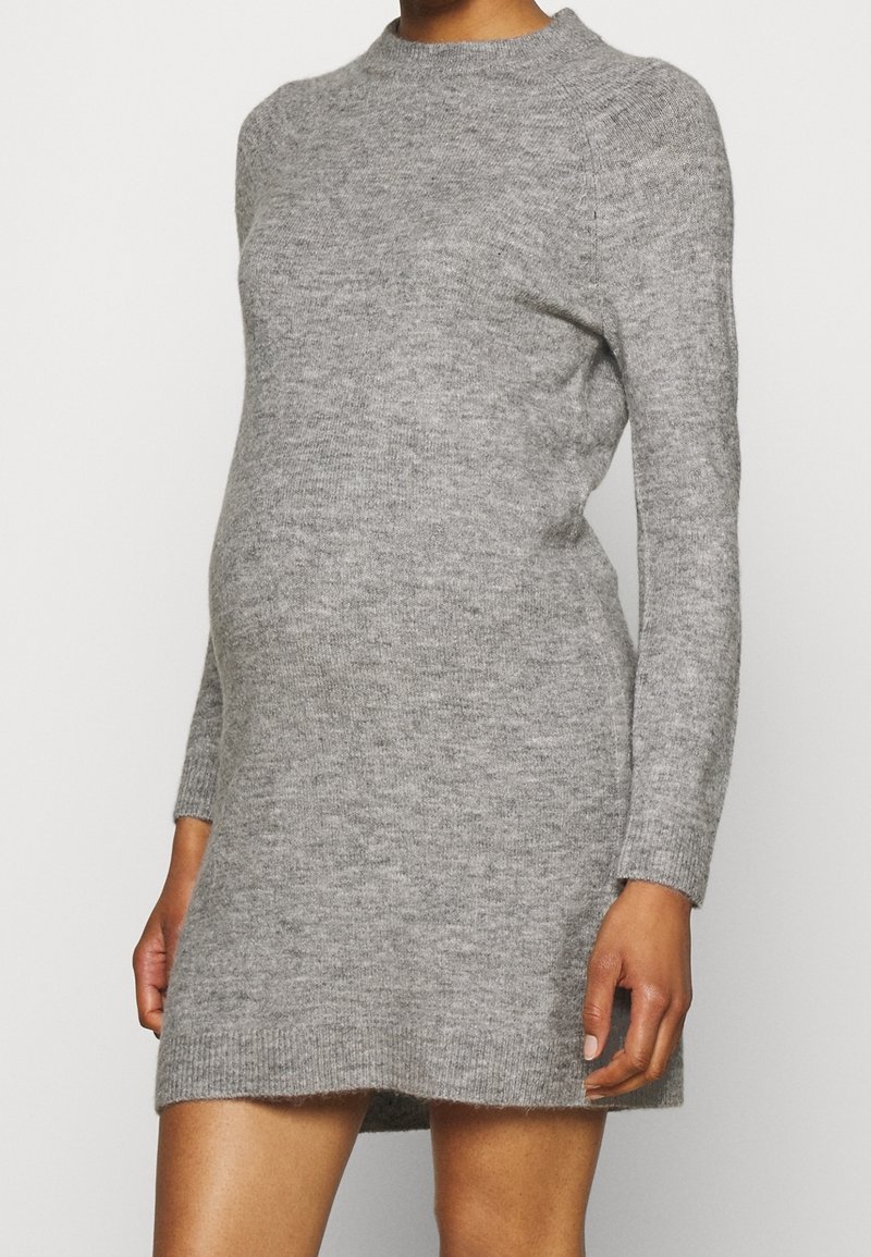 Personne portant une robe pull grise, ajustée, à manches longues, qui s'étend jusqu'à mi-cuisse, montrée du cou aux jambes.