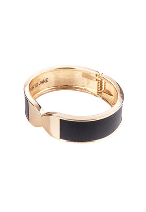 Armband aus goldenem Metall mit einer Einlage aus schwarzem Leder, runder Form und flachen Kanten sowie einem einfachen Verschlussmechanismus.
