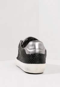 Sneaker nera con motivo a serpente testurizzato, dettagli metallici argento sul tallone e suola in gomma bianca. La vista posteriore mostra la forma e i dettagli della scarpa.