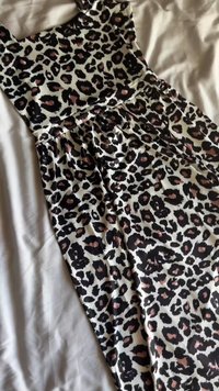 Leopardenmusterkleid mit tailliertem Oberteil und ausgestellt Rock; Farben sind Schwarz, Pink und Weiß; hergestellt aus glattem Stoff mit weicher Textur.