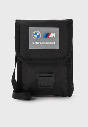 Musta BMW Motorsport -merkitty pussukka läppäkannella, Puma-logo edessä ja säädettävä hihna sivulla.