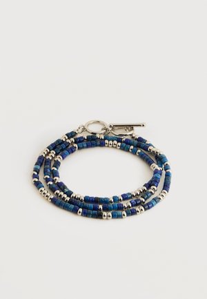 Trysluoksnis apyrankė su mažais mėlynais kvadrato formos ir sidabrinėmis apvaliomis karoliukėmis, su sidabrine užsegimo kilpa, pateikta baltoje fone.