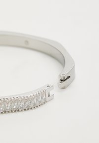 Zilveren bangle armband met een rij rechthoekige heldere stenen. Een gladde, gepolijste oppervlakte met een strak, hedendaags ontwerp.