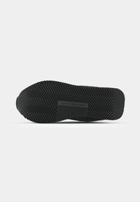 Fekete gumitalpú sneaker, cikk-cakk mintázattal, középen márkázott. Simára csiszolt felület, lekerekített élek.