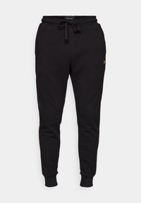 Schwarze Baumwoll-Jogginghosen mit elastischem Bund, Kordelzug und gerippten Bündchen. Mit einem kleinen gelben Logo auf dem linken Oberschenkel.
