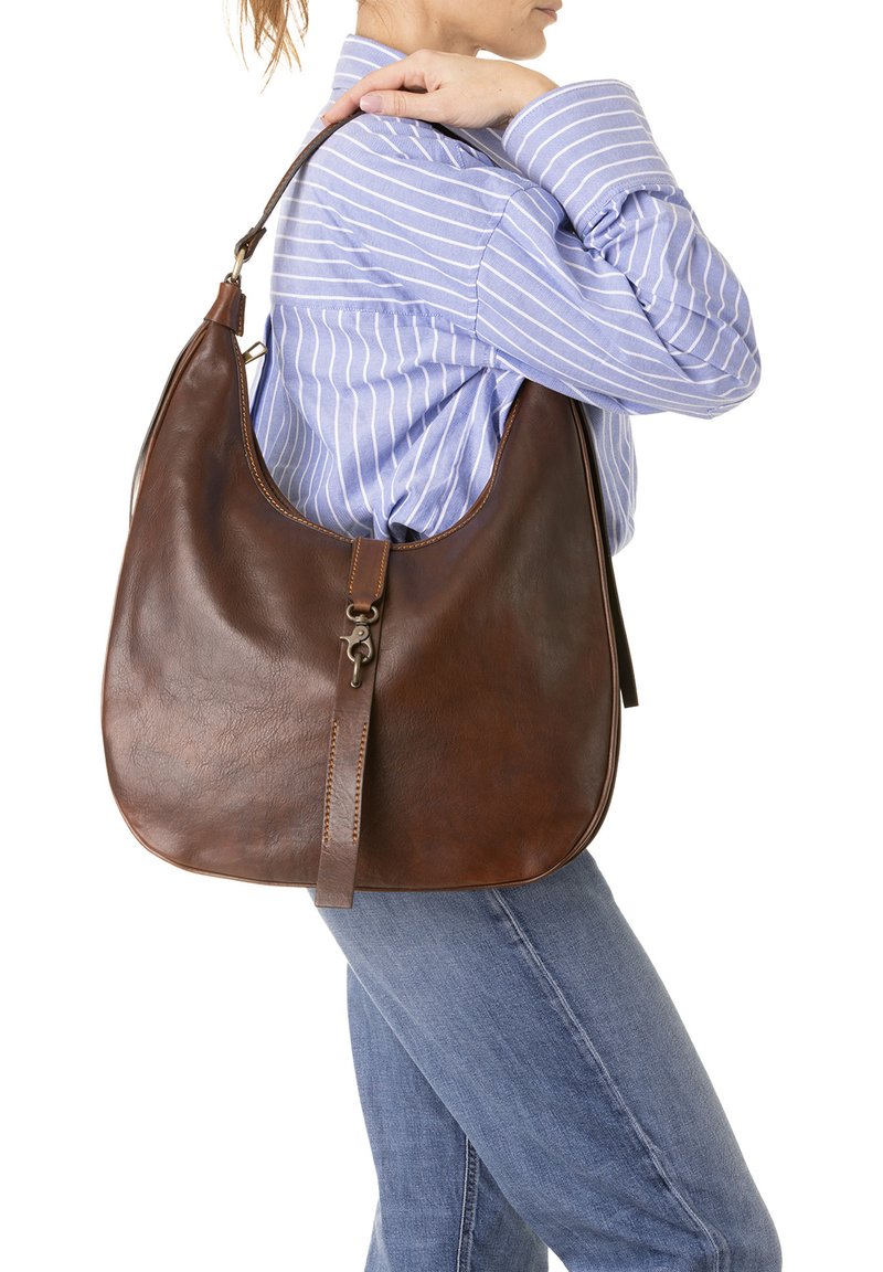 Sac à bandoulière en cuir marron avec une forme incurvée, doté d'une longue bandoulière et d'un fermoir décoratif à l'avant, présenté sur un fond clair.