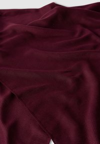 Burgundowy szalik z miękkiego, teksturowanego materiału z subtelnymi detalami w zygzak, ułożony i złożony, aby pokazać głębię i ruch.