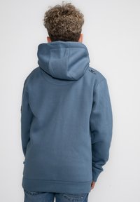 Felpa blu in morbido tessuto, con un ampio cappuccio, polsini a coste e un fit rilassato. Include dettagli di branding discreti.