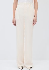 Pantalon large beige avec des rayures verticales, fabriqué en tissu léger. Il présente une taille haute et un devant plat avec des poches latérales.