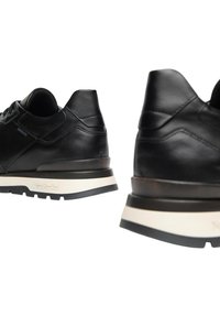 Sneakers in pelle nera con una texture liscia, dotati di un plantare bianco a contrasto, lacci rotondi e un branding minimale su un lato.