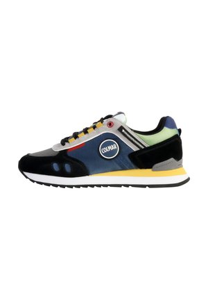 Zapatillas deportivas con una mezcla de tejidos en gris, negro y azul, que presentan un logo redondo, detalles en amarillo y una suela blanca. Materiales texturizados utilizados.